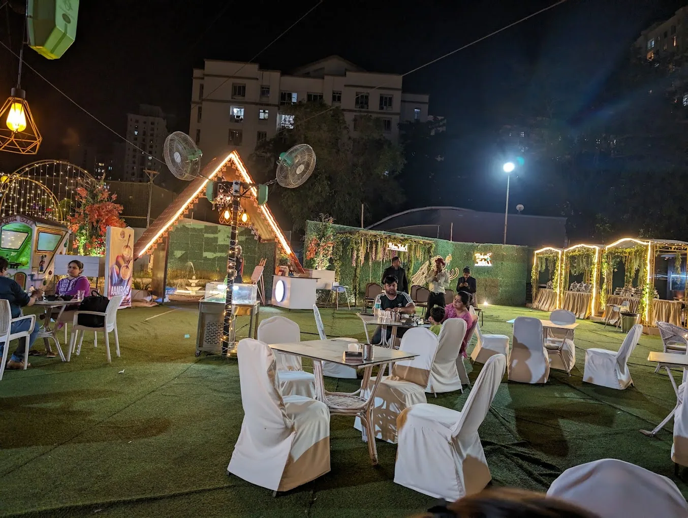 A party lawn at night under string lights